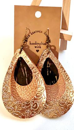 two pairs of gold and black tear shaped earrings in front of a wooden hanger