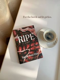 a cup of coffee next to a book on a white table with the title ripe