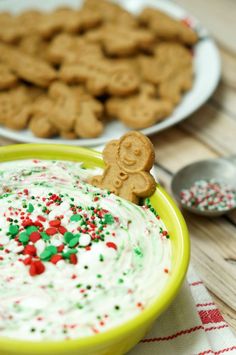 a bowl of white frosted christmas dip with gingerbread cookies in the background