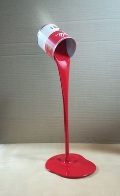 a can is pouring red liquid into a cup