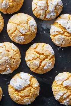 freshly baked cookies with powdered sugar sitting on a black counter top, ready to be eaten