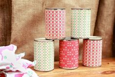 four canisters sitting on top of a wooden table next to a cloth bag