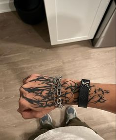 a man with tattoos on his arm holding onto a chain and wearing two bracelets