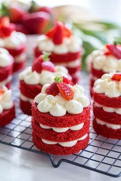 some red velvet cakes with white frosting and strawberries on top are sitting on a cooling rack