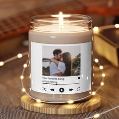 a candle that is sitting on a table with lights around it and an image of a couple