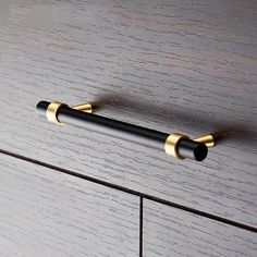 a black and gold handle on a wooden cabinet