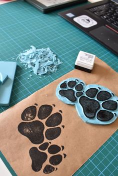 a brown paper bag with black paw prints on it next to a laptop and scissors