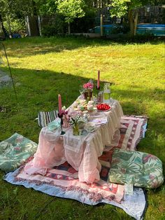 a picnic table set up in the middle of a grassy area with flowers and candles on it