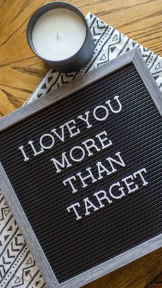 a sign that says i love you more than target next to a candle on a table