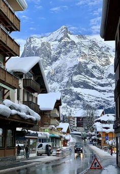 the mountains are covered in snow as people walk down the street