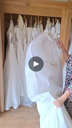 a woman holding up a dress in front of wedding gowns