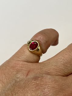 Amazing vintage 14k yellow gold created ruby ring, circa 1960s! The created red ruby weighs an estimated 1.21 carats, is oval cut, and is a stunning deep red. The setting contains a classic design with a high polish finish. Classic statement piece of fine retro jewelry showcasing a stunning created ruby, circa 1960s! ERA - Circa 1960s, Retro METAL / MATERIAL - 14k yellow gold, 1 created ruby (estimated 1.21 carats) [Synthetic ruby contains essentially the same chemical composition & properti Classic Red Ruby Ring, Oval Cabochon, Classic Red Ruby Ring With Oval Cabochon, Vintage Red Signet Ring With Oval Cabochon, Oval Cabochon Red Ruby Ring In 14k Gold, Red Ruby Oval Cabochon Ring In 14k Gold, Vintage Red Oval Cabochon Signet Ring, Classic Red Signet Ring Stamped 14k, Heirloom Style Ruby Ring, Vintage Ruby Signet Ring In Yellow Gold