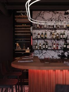 a bar with several bottles of wine on the wall and chairs in front of it