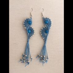 two pairs of blue beaded earrings with pearls and beads on them, sitting on a white surface