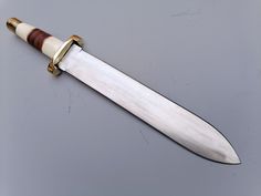 a knife with a wooden handle on a gray surface, it appears to be from the early 20th century