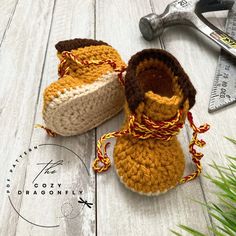 two crocheted baby booties sitting on top of a wooden floor next to a wrench