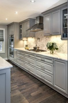 a large kitchen with gray cabinets and white counter tops is seen in this image from the front view