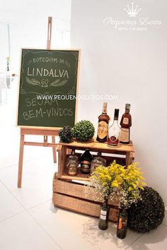 a sign that is on top of a wooden crate with liquor bottles and flowers in front of it