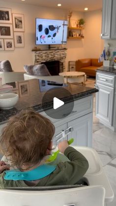 a toddler sitting in a high chair watching television