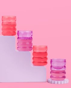 the pink and purple vases are lined up on top of each other in different colors