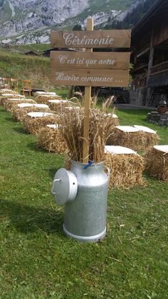 a sign that is on top of a fire hydrant in the grass near hay bales