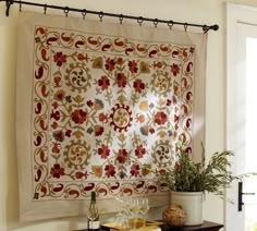 a table topped with a wine glass next to a wall hanging