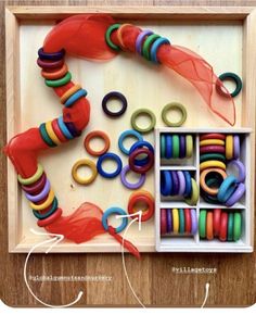 an assortment of colorful beads and rings in a wooden box