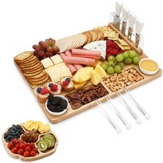 an assortment of cheeses, crackers, and fruit on a wooden platter