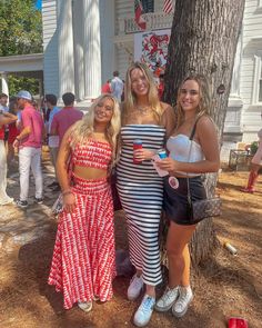 three women standing next to each other near a tree