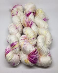 several skeins of white yarn with pink and yellow stripes on the top, all in different colors