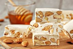 several pieces of food sitting on top of a wooden cutting board next to some nuts