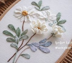 three white flowers are sitting on a piece of fabric in front of a wooden frame