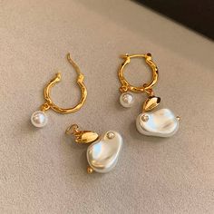 These Faiga Pearl Drop Gold-Plated Earrings feature an elegant and playful design, blending classic beauty with a touch of modern charm. The earrings showcase a unique drop-shaped pearl accented by a delicate gold-plated leaf and smaller pearls for an extra hint of luxury. The hoops are crafted from high-quality gold-plated brass, offering durability and a radiant shine. Perfect for elevating both casual and formal looks, these earrings are a versatile addition to any jewelry collection. Details: Material: 14K gold-plated brass, synthetic pearls Color: Gold and Silver with pearl accents Earring Length: 3.5cm Weight: Lightweight and comfortable for all-day wear Missy Jewelry Pearl Earrings Collection Trendy Gold Pearl Charm Earrings, Jewelry Pearl Earrings, Pearl Jewelry Necklace, Jewelry Pearl, Natural Stones Necklace, Gold Statement Earrings, Natural Stone Jewelry, Natural Stone Bracelets, Pearl Jewellery Earrings