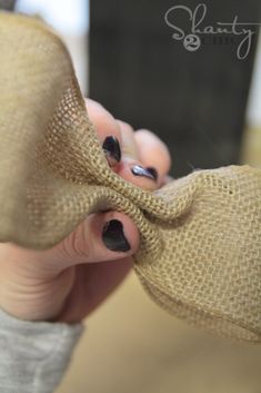 a person with black nail polish holding a burlap bow