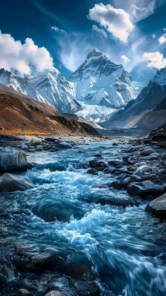 a river running through a lush green valley under a cloudy blue sky with mountains in the background