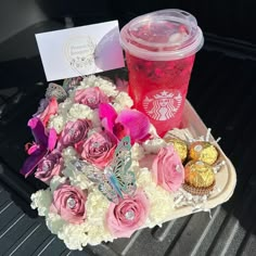 a starbucks drink and some flowers in the back of a car with a card on it