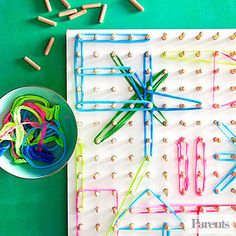 a bunch of pins sitting on top of a board next to a bowl of colored pencils