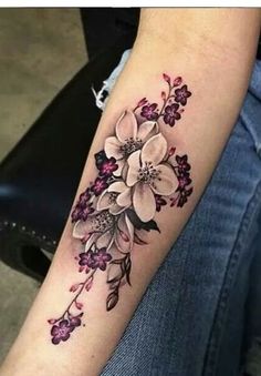 a woman's arm with flowers on it, and the tattoo is done in black ink