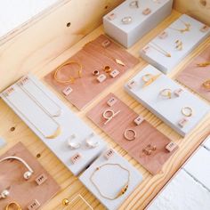 many different types and sizes of jewelry on display in wooden boxes with earring hooks