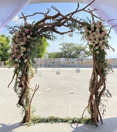 an archway decorated with flowers and greenery for a wedding or reception area at the beach