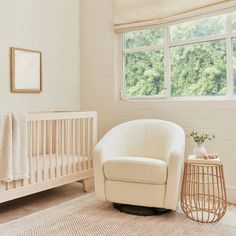 a baby's room with a crib, chair and window