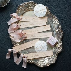 place cards are placed on a silver plate with pink ribbons and tags attached to them