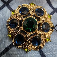 Floral Pin Brooch From Neiman Marcus Gold Tone Setting - Ornate Details Set With Large Green Stone In Center, Surrounded By Blue Stones & Light Green Small Stones Around Edge Comes With Dark Blue Mesh Pouch Approx. 1.75" W & 0.75" D Original Tag Still Attached Elegant Blue Jeweled Brooches, Neiman Marcus Jewelry, Antique Green Multi-stone Jewelry, Luxury Antique Green Brooch, Vintage Gold Brooch, Vintage Multi-stone Yellow Gold Brooches, Vintage Green Rhinestone Brooch, Vintage Multi-stone Gold Brooches, Floral Pins