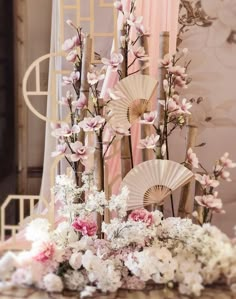 an arrangement of flowers and fan on a table