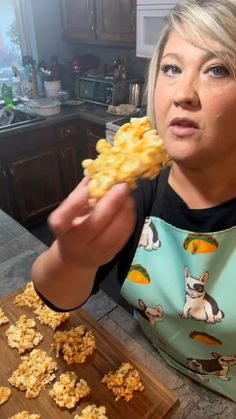 a woman is holding up some food in her hand while sitting at the kitchen table