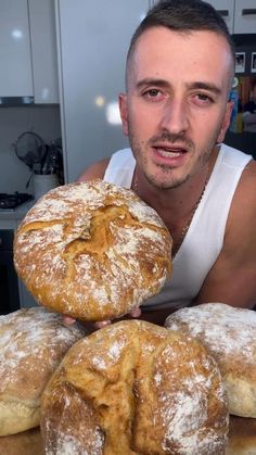 a man sitting in front of a pile of doughnuts covered in powdered sugar