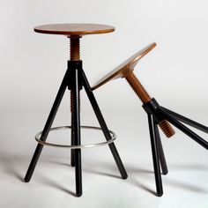 two stools with wooden legs and metal feet, one on top of the other