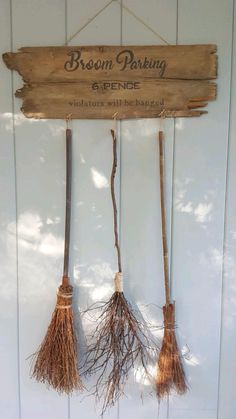 three brooms hanging from a wooden sign that says broom parking