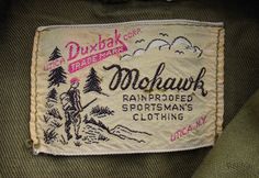 a label on the back of a green jacket with trees and mountains in the background