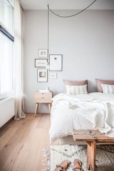 a bedroom with white walls and wooden flooring is pictured in this image, the bed has